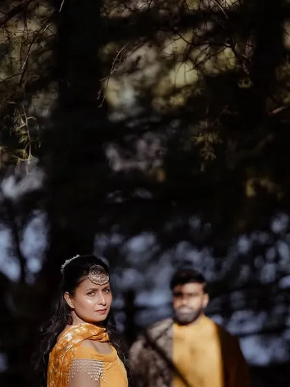 An artistic and moody portrait of the bride during her Haldi ceremony, with a focus on her expressive eyes and traditional jewelry.