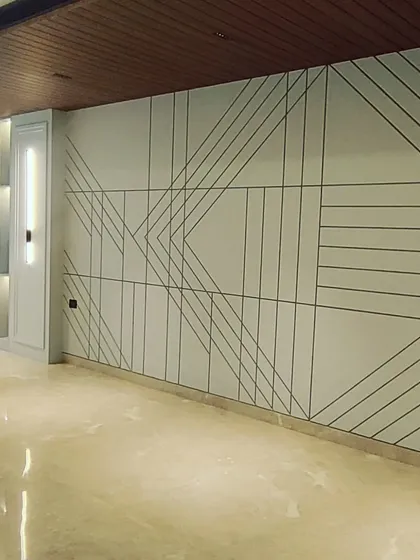 Another example of detailed wall paneling work in an unfurnished space. The clean lines and geometric patterns on the wall are installed, and the polished marble floor is complete.