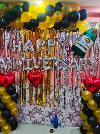 A 9th anniversary home decoration with a black and gold theme. The setup includes a balloon arch, 'Happy Anniversary' foil letters, and heart-shaped balloons.