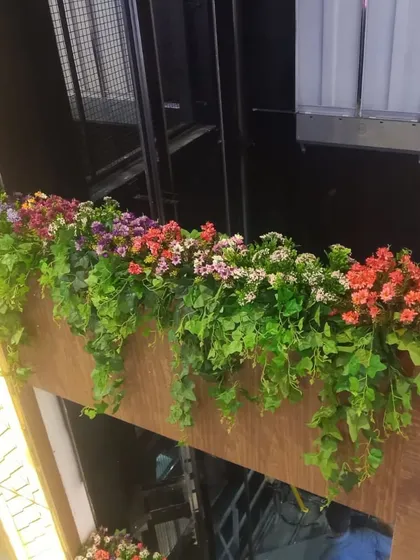 A close-up of the mall ledge decoration, showing the vibrant mix of pink, purple, and orange flowers nestled in green ivy.