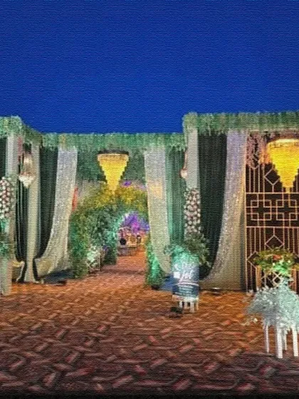 This elegant venue entrance features green and white drapes, sequin curtains, and hanging chandeliers. A floral archway in the center leads guests into the main event area.