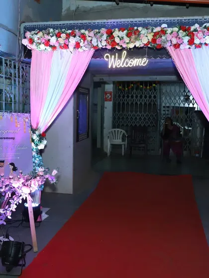 A beautiful entrance arch for an engagement ceremony. We used drapes, flowers, a red carpet, and a neon 'Welcome' sign to greet the guests.