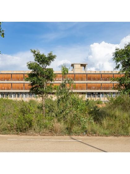 The RSL Office building viewed from a distance, its horizontal form blending with the landscape. The structure is built with CSEB masonry and features a terracotta jaali facade for passive cooling and light diffusion.