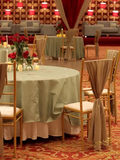 Guest seating for the after-party, with sage green tablecloths and elegantly draped chairs, set against the vibrant red lounge area.