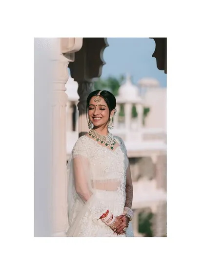 Framed by the classic arches of a Pushkar palace, Sakshi's joyful smile shines. This portrait beautifully combines architectural elements with the bride's natural grace.