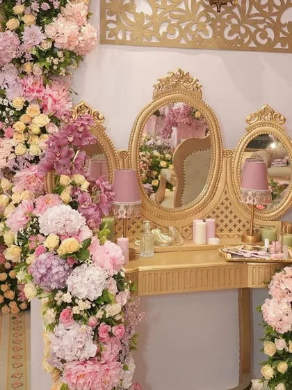 A golden vanity table surrounded by lush floral arrangements, part of the regal bachelorette party decor.