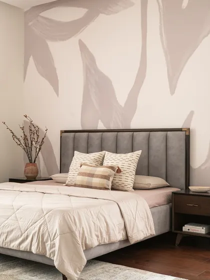 The master bedroom features a custom-designed abstract wallpaper that acts as a piece of art. This is paired with a simple, upholstered grey bed and warm wood bedside tables for a balanced and serene look.
