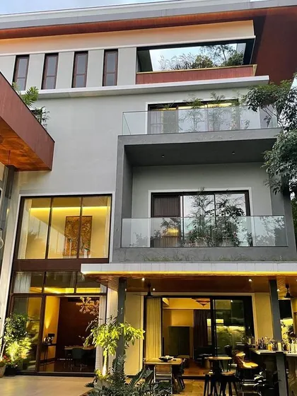 The exterior of this multi-level home in Koramangala features cantilevered balconies and a covered outdoor bar and seating area. We designed these spaces to extend the living area outdoors, perfect for entertaining and relaxation.