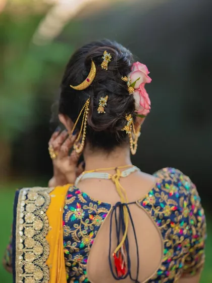 A detailed look at the messy khopa, adorned with a chandrakor pin and fresh flowers. This modern take on a traditional hairstyle is a favorite among my brides.