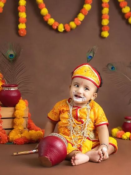 A baby as little Krishna with "butter" on his face, holding a flute prop.