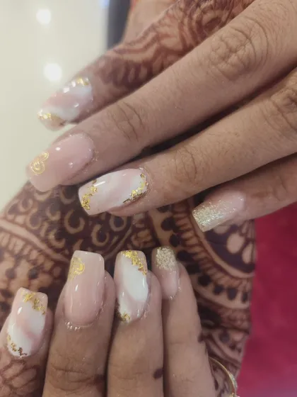 This beautiful manicure combines a soft pink and white marble base with delicate gold foil accents for a touch of sophisticated sparkle.