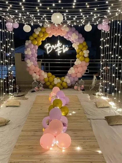 A beautiful terrace setup for a 'Bride to Be' party, featuring a balloon ring backdrop, a low-seating arrangement, and a canopy of fairy lights.