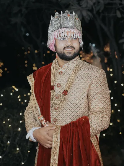 A classic portrait of the groom in his wedding attire. The soft, out-of-focus lights in the background create a beautiful bokeh effect, making him stand out.
