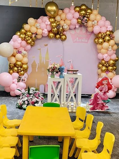 The completed princess castle stage with the balloon arch, ready for the party, with a kids' table set up in the foreground.