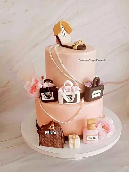 Celebrating a 40th birthday for a true fashionista. This two-tier cake features a collection of iconic, handcrafted luxury items, including miniature bags from Fendi and Prada, a Dior perfume bottle, and a stylish shoe topper.