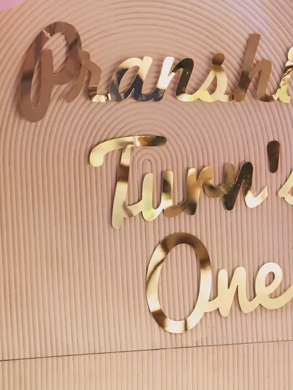 A close-up of the elegant gold mirror text for "Pranshi Turn's One," which adds a reflective, high-end finish to the main backdrop.