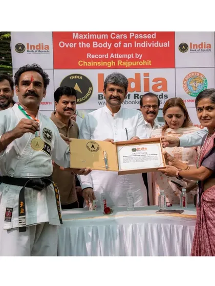 Receiving the official certificate from the India Book of Records for successfully having 21 cars pass over my body. A proud moment shared with guests and supporters.