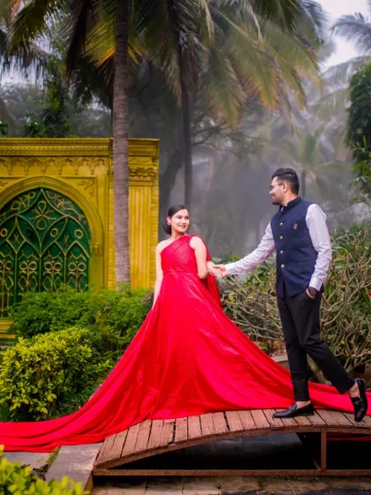 A couple walks across a bridge in our garden, with a stunning yellow and green arched gate in the background, showcasing our diverse architectural elements.