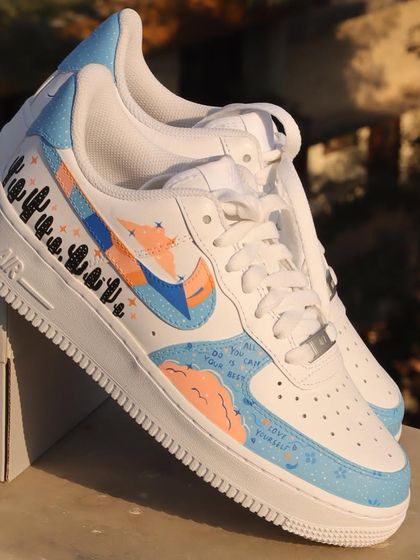 This freehand design on a pair of Nike Air Force 1s features a dreamy, abstract aesthetic with a pastel color palette, cloud-like shapes, and a row of cute cacti.