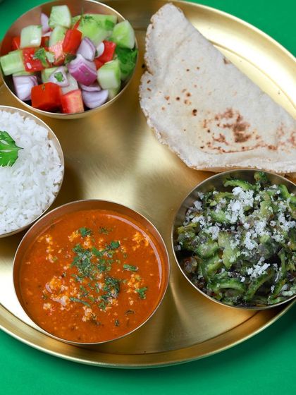 A simple, satisfying veg thali with paneer bhurji, a dry vegetable preparation, rice, salad, and roti. Perfect for a light yet filling lunch.