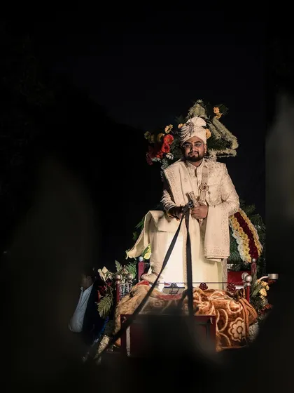 An artistic view of the groom on his horse, framed by a foreground element. This creative composition adds depth and a sense of looking in on a private, grand moment.