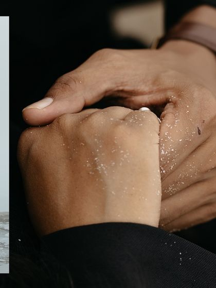 A detailed close-up of the couple holding hands, with sand on their fingers, symbolizing their connection to the beach setting.
