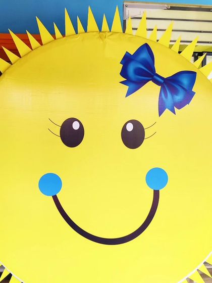 A close-up of a giant smiling sun prop, perfect for a "You are my sunshine" or "First Trip Around the Sun" theme.