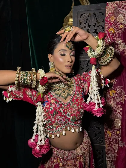 This image captures the playful side of the bride, adorned with floral kaleeras. The makeup is kept fresh and glowing to match the vibrant, celebratory mood.