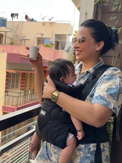 This post for LittleBum's baby carrier highlights the benefit of being hands-free. I'm shown enjoying a cup of coffee on the balcony while keeping Gauri close and comfortable, a perfect visual for busy moms. The post also includes a discount code to encourage purchase.