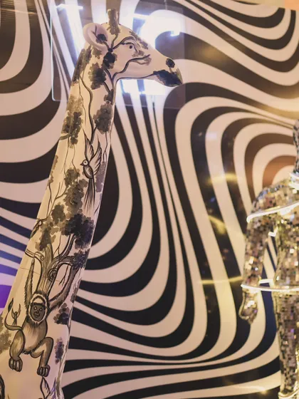 A close-up of the unique decor elements, including a hand-painted giraffe statue and a disco-ball mannequin against a psychedelic backdrop. We source and create props that make a brand's event truly one of a kind.