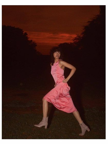 A dynamic pose captured at dusk for the Sruti Dalmia campaign. The styling of the pink dress and modern boots against the dramatic red sky creates a strong, fashion-forward image filled with energy and attitude.