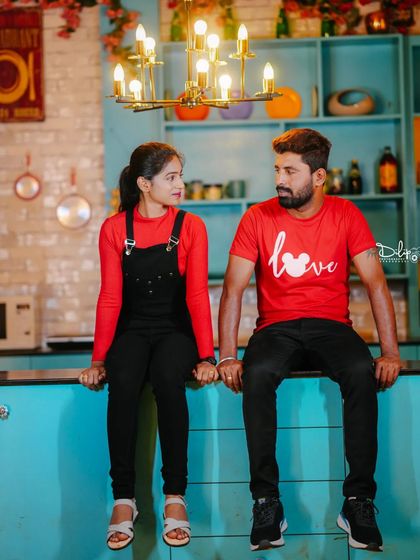 Another angle of the couple in the kitchen set, holding hands.