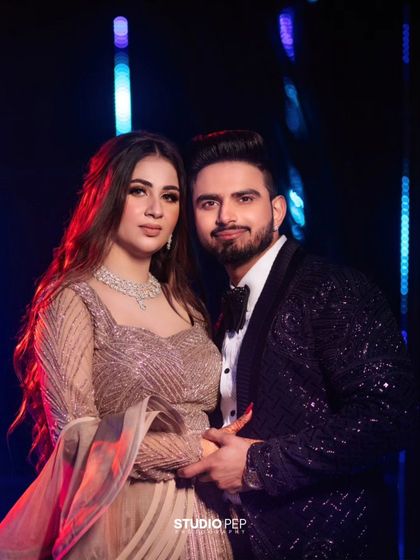 A close-up portrait of the couple against a vibrant, colorful background. The red and blue lighting adds a dynamic and glamorous feel to this engagement shot.