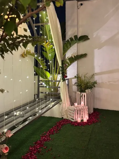 The romantic terrace decor at night, with fairy lights creating a curtain of light behind the floral arch.