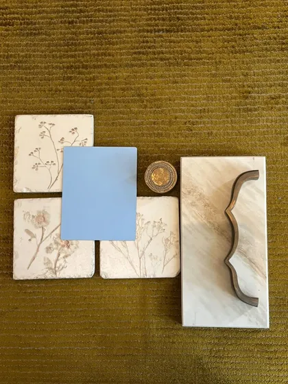 A mood board exploring a gentle contrast of materials. The delicate floral tiles, a pop of sky blue, and a uniquely curved metal handle against a marble slab are the beginning of a kitchen with a soft, artistic personality.