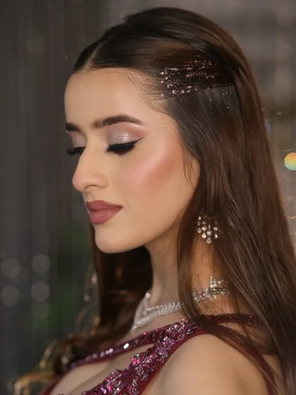 A close-up of the eye makeup and hair. The glitter in her hair parting adds a unique, glamorous touch to the look.