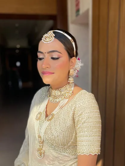 A front view of the bride with her pearl and hydrangea bun. The hairstyle is designed to beautifully accommodate her matha patti and other jewelry.