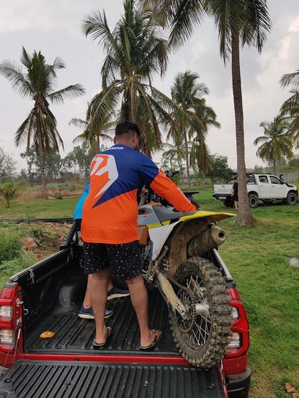 Teamwork extends beyond the track. Here, our members help load a dirt bike onto a truck after a long day of riding. Many hands make light work.