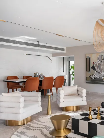 The living and dining areas of the Evelyn project are designed to flow seamlessly. This view shows the connection, with the bold forms of the living room furniture leading the eye toward the elegant dining space in the background.