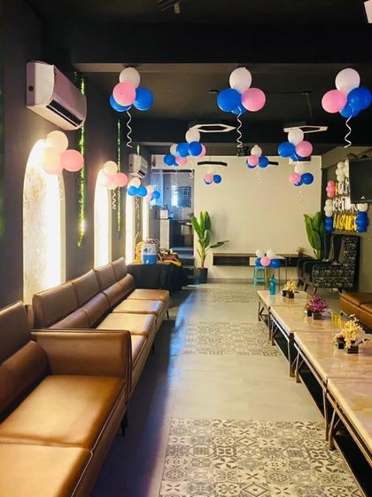 A wide view of a cafe decorated with simple pink and blue balloon clusters, showing how even minimal decoration can make a space party-ready.