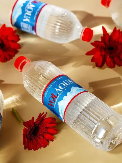 A pattern-based shot of Volaqua bottles and red flowers. This flatlay creates a bold and visually interesting graphic, perfect for social media or ad banners.