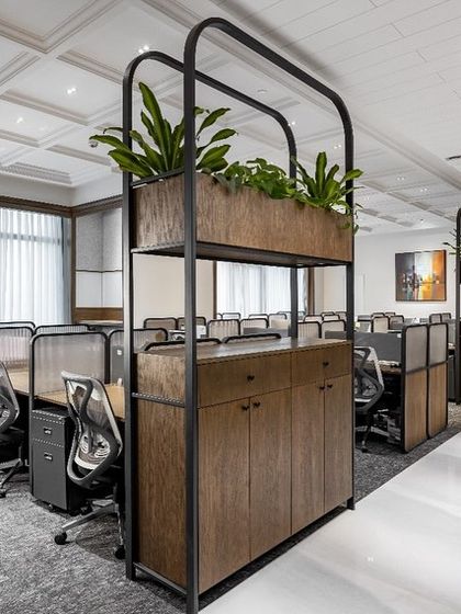 The workstation area at the VRS Office is bright and organized. The custom partitions with integrated planters add a biophilic element, while the coffered ceiling and ample natural light contribute to a productive and pleasant work environment.