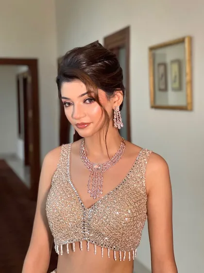 A beautiful portrait of a client ready for a party. The high bun with soft, face framing pieces creates a look that is both elegant and effortlessly chic.