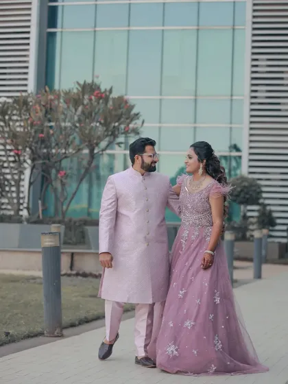 A walking shot of the couple, showing off their beautiful outfits against a modern architectural background.