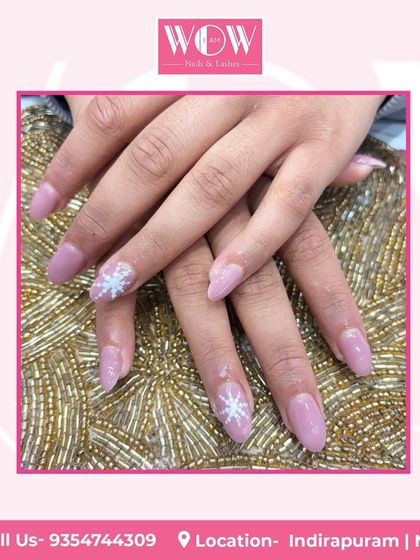 A delicate and wintry design. This look features a soft pink base with a sparkling snowflake accent nail, perfect for the holiday season.