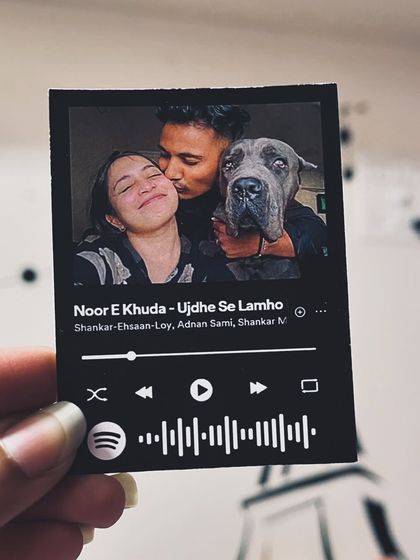 A sweet moment between a couple and their dog, immortalized on a Spotify music card.