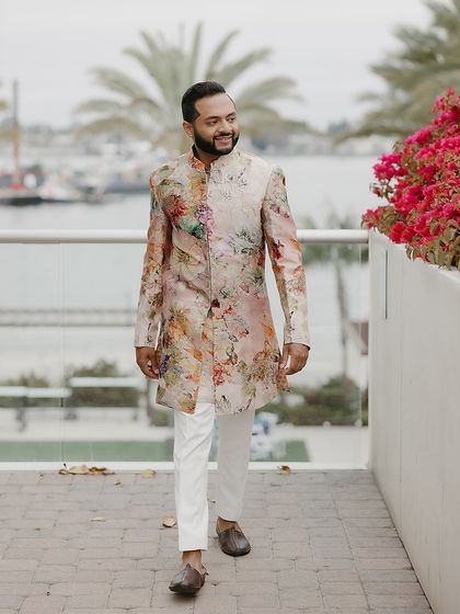 A confident and happy groom on his Sangeet day. His custom floral sherwani by Varun Bahl was styled to be original and full of refined ease.