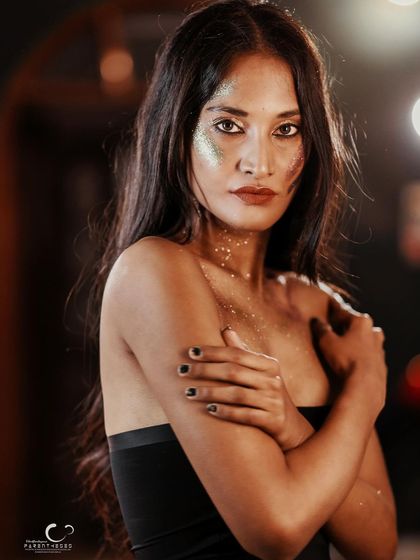 A vulnerable yet strong pose. The way she holds herself, combined with the artistic glitter makeup, tells a story of self-protection and inner light.