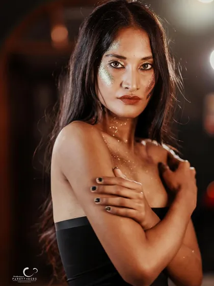 A vulnerable yet strong pose. The way she holds herself, combined with the artistic glitter makeup, tells a story of self-protection and inner light.