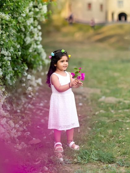 A lovely portrait of a girl with a floral headband, with a beautiful pink color flare adding a creative touch.